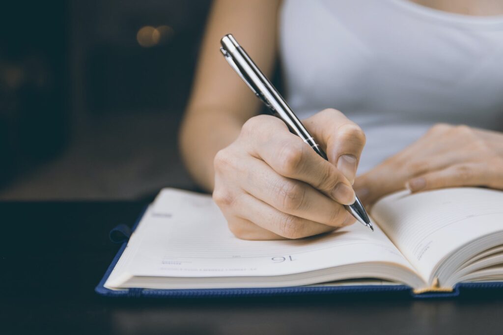 photo of a girl writing on her notebook to deal with a heartbreak