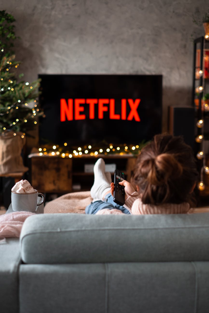 Movies And Series To Watch on Netflix in March 2024 back view of a woman sitting on a sofa and watching television